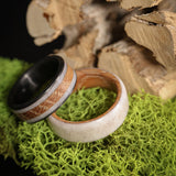 Deer antler wedding band with whiskey barrel wood and carbon fiber sleeve on moss