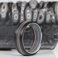 Fordite Men's Ring with Carbon Fiber Rails On Fordite Backdrop