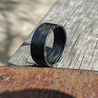 Ultralight Men's Ring with Wave Carbon Fiber On A Wooden Plank