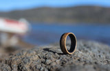 Men's whiskey barrel ring with carbon fiber outside on a rock