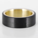 men's gold wedding ring with carbon fiber close up