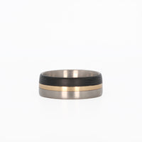 titanium ring with gold and carbon fiber inlays laying flat