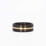 carbon fiber men's wedding ring with yellow gold band laying flat